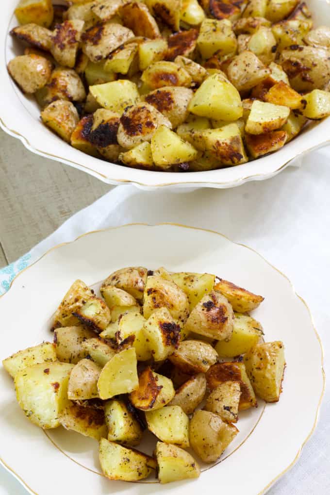 Close up view of a plate and bowl of crispy roasted ranch potatoes.