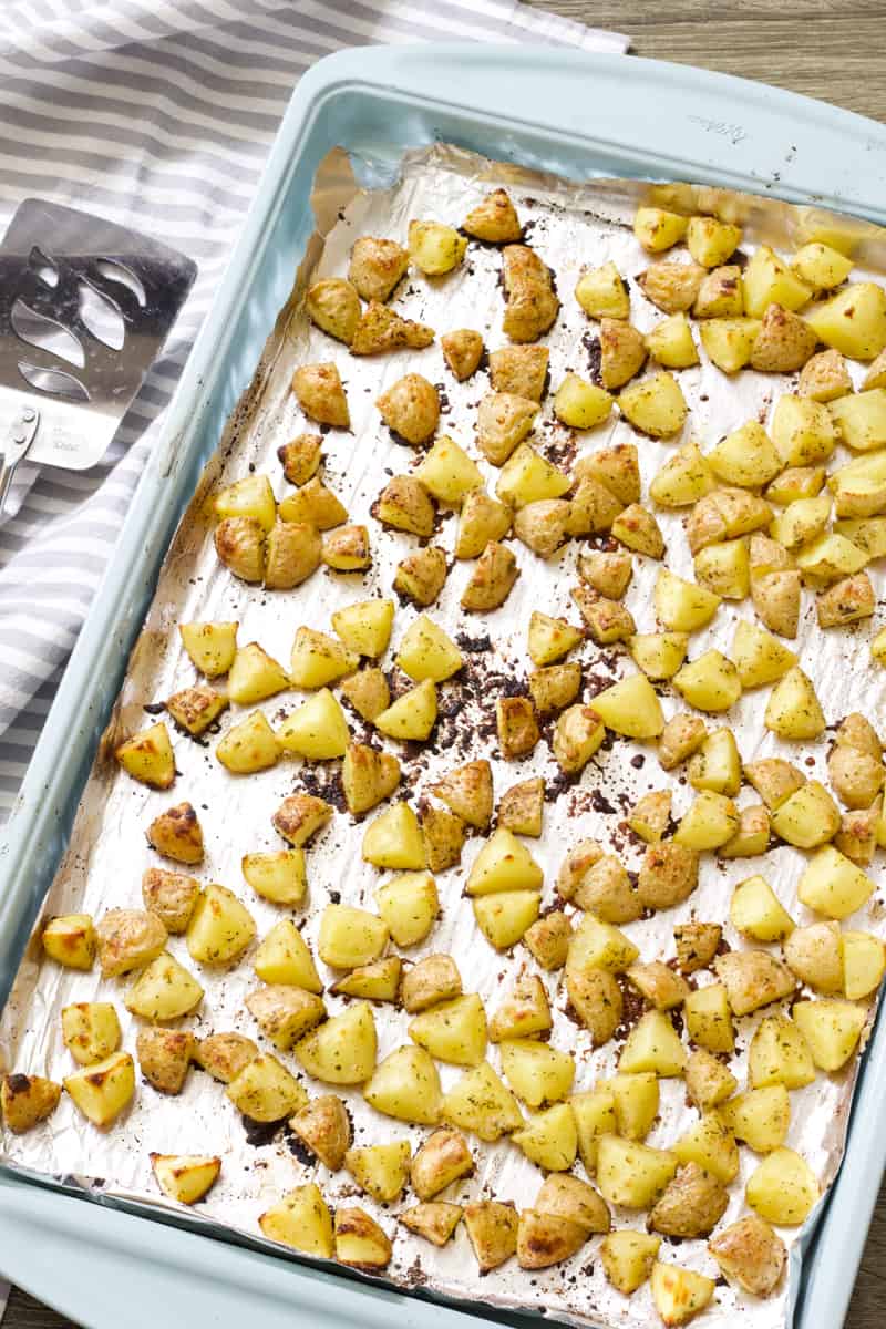 Overhead shot of crispy roasted ranch potatoes on a light blue sheet pan.