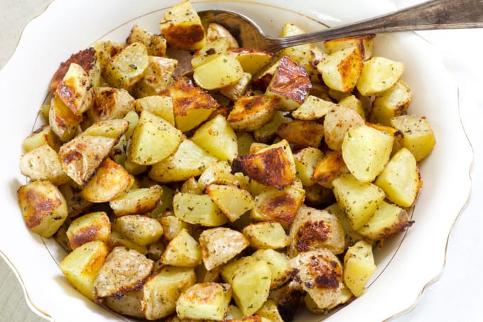 Close up view of a bowl of potatoes with the words crispy roasted ranch potatoes.