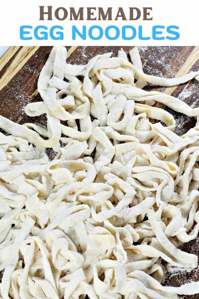 A close up view of homemade egg noodeles on a two-tone wood cutting board.