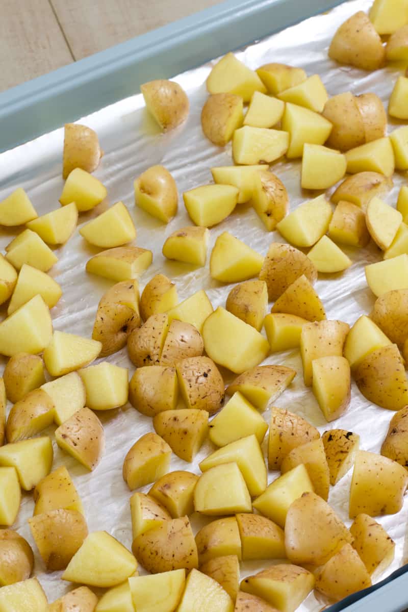 Close up shot of raw cut up potatoes on a sheet pan ready to be seasoned.