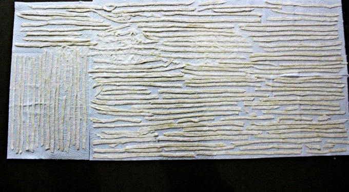 long egg Noodles spread out on paper towels to dry on a counter.
