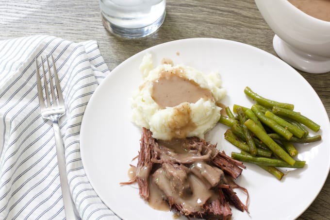Overhead shot of a plate with roast beef, mashed potatoes, gravy and green beans.