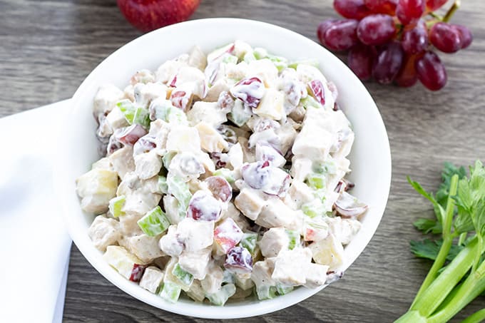 A close up overhead view of a bowl of chicken salad with grapes and celery.