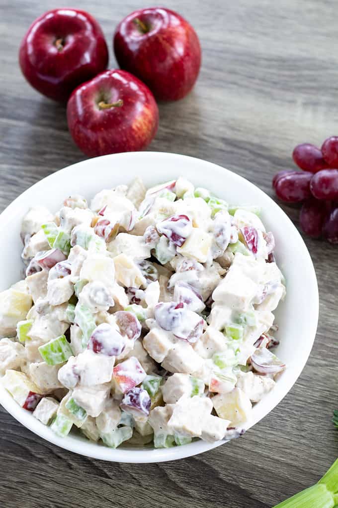 A close up overhead view of a bowl of chicken salad with grapes and celery.