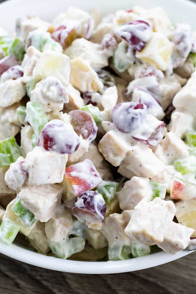Very close up view of chicken salad in a white bowl.
