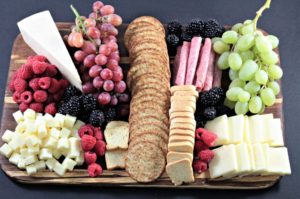 This Perfect Party Cheese Board features Stella Cheeses, Genoa Salami, crackers, mini toast, red and green grapes, raspberries and blackberries.
