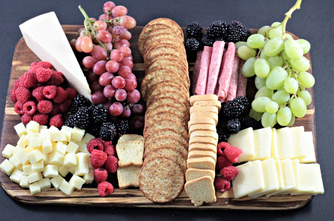 Perfect Party Cheese Board features Stella Cheeses, Genoa Salami, crackers, mini toast, red and green grapes, raspberries and blackberries. 