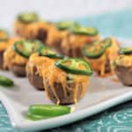 Side view of jalapeno potato popper appetizer on a plate. with a jalapeno ring.