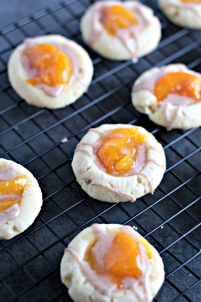 Peach Pie Thumbprint Cookies feature a shortbread type cookie topped with peach pie filling and drizzled with a cinnamon glaze. Mini peach pie in a cookie!