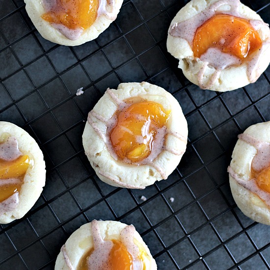 Peach Pie Thumbprint Cookies feature a shortbread type cookie topped with peach pie filling and drizzled with a cinnamon glaze. Mini peach pie in a cookie!