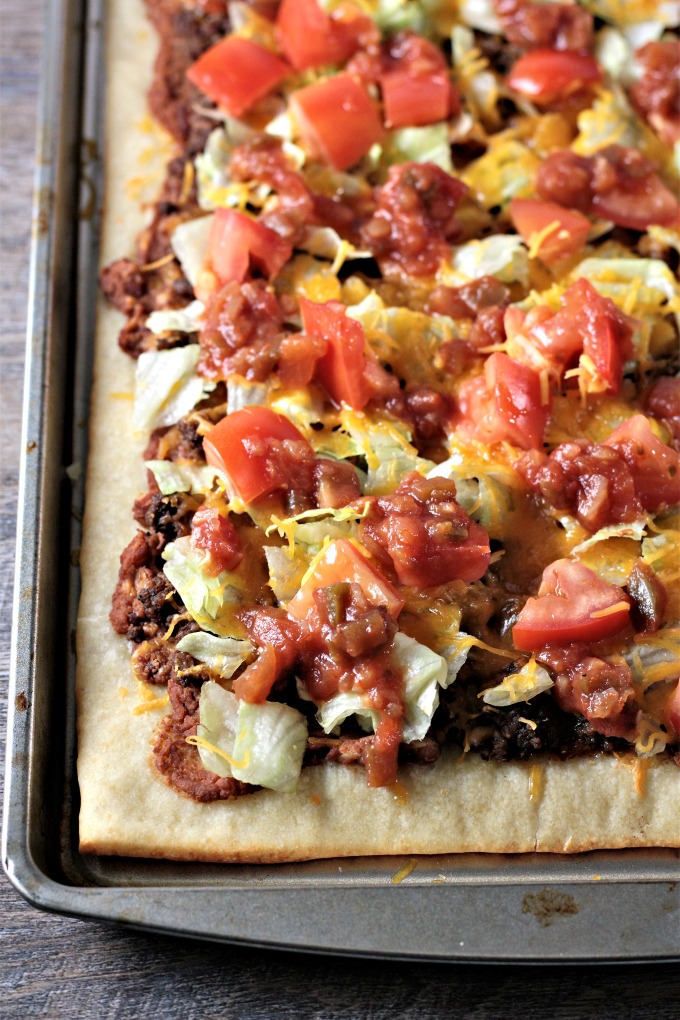 Super Easy Taco Pizza: Premade pizza dough, refried beans, seasoned ground beef, cheese, lettuce, tomatoes, and salsa. Quick, easy and kid friendly.