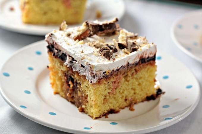 Twix Poke Cake combines boxed yellow cake mix, caramel topping, chocolate pudding, whipped topping and Twix candy bars to make an easy and yummy dessert!