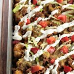Loaded Beef Tater Tots (Totchos) feature nacho ingredients (ground beef, cheese, sour cream, salsa, and tomatoes) on tater tots instead of tortilla chips.