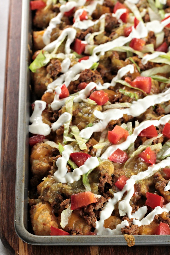 Loaded Beef Tater Tots (Totchos) feature nacho ingredients (ground beef, cheese, sour cream, salsa, and tomatoes) on tater tots instead of tortilla chips. 