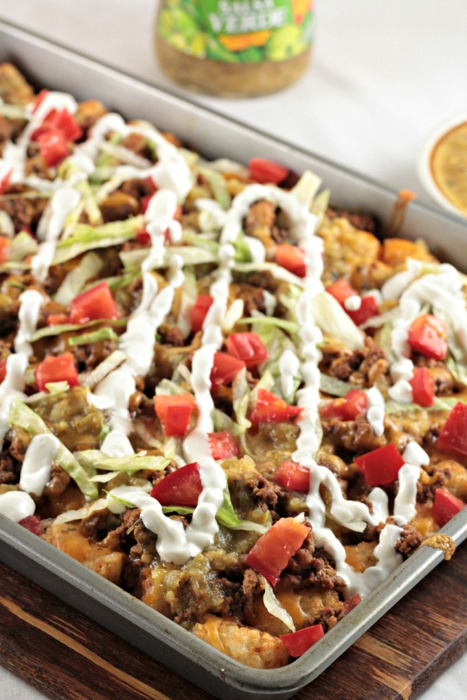 Loaded Beef Tater Tots (Totchos) feature nacho ingredients (ground beef, cheese, sour cream, salsa, and tomatoes) on tater tots instead of tortilla chips. 
