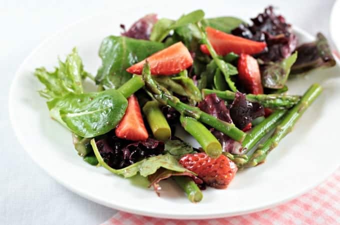 Asparagus Strawberry Mixed Green Salad features fresh asparagus, strawberries and mixed greens (red, green and romaine lettuce, spinach, arugula, and raddichio) and is topped with a simple viniagrette made from olive oil, balsamic vinegar and a little bit of salt. Fresh and delicious!