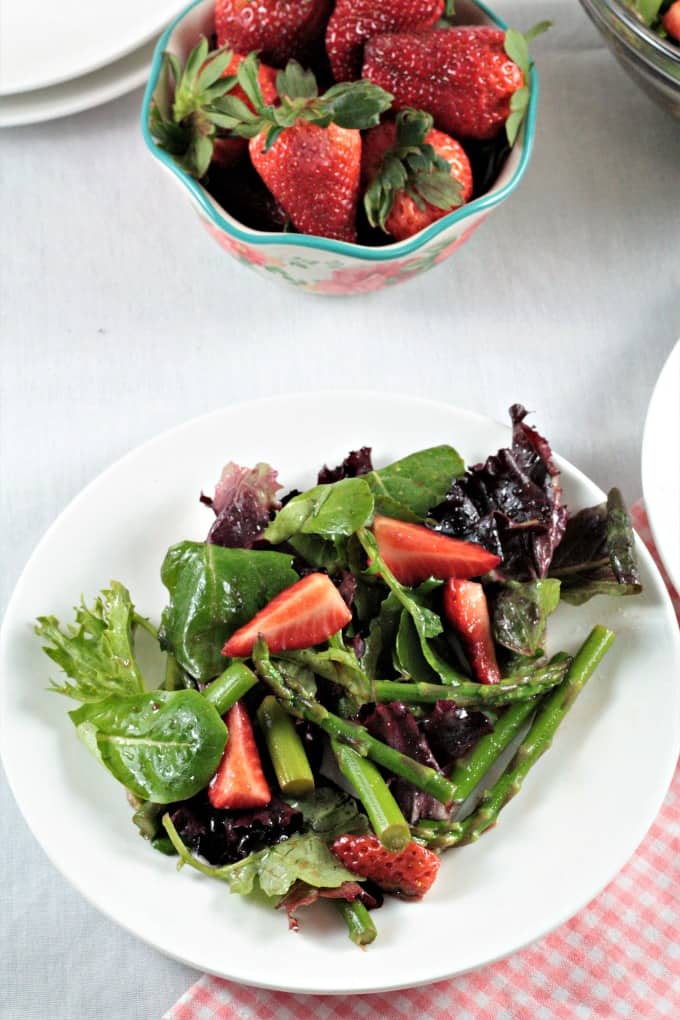 Asparagus Strawberry Mixed Green Salad features fresh asparagus, strawberries and mixed greens (red, green and romaine lettuce, spinach, arugula, and raddichio) and is topped with a simple viniagrette made from olive oil, balsamic vinegar and a little bit of salt. Fresh and delicious!