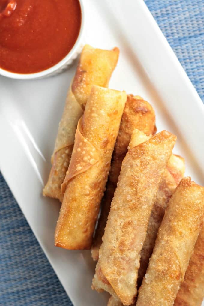 Pepperoni Pizza Egg Rolls feature mozzarella string cheese, sliced pepperoni and Italian seasoning wrapped in an egg roll wrapper and the deep fried to perfection. This is an easy and fun appetizer or snack great for kids and adults alike. Mindy's Cooking Obsession