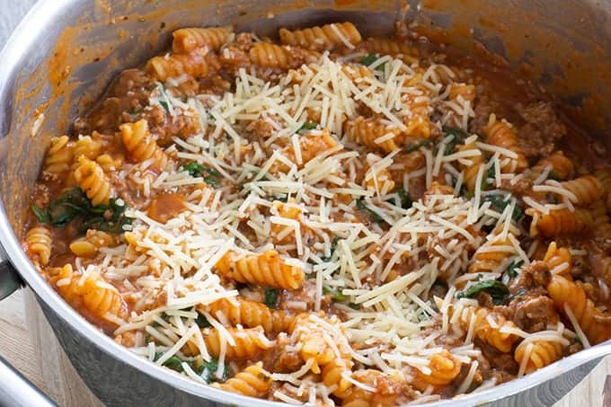 A pan of one pot meaty marinara pasta topped with grated parmesan cheese.