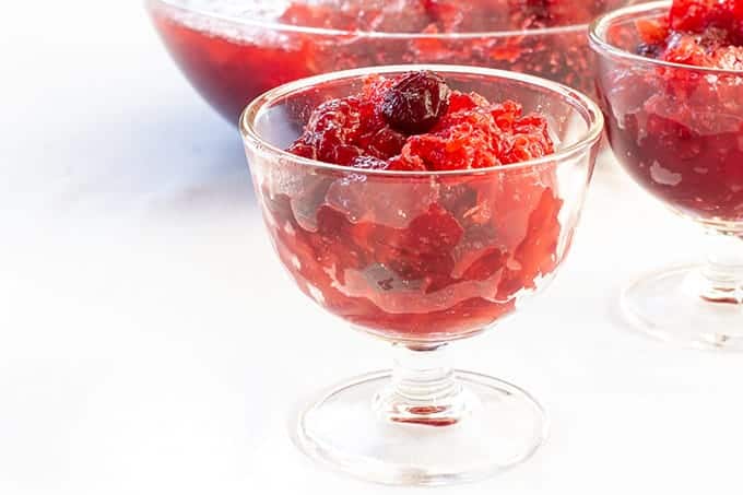 Side view of a small bowl of jello salad with a large bowl full of it in the background.