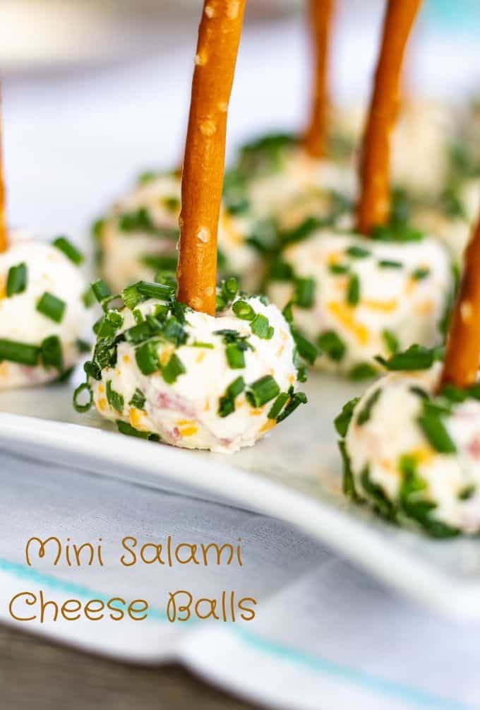 Mini Salami Cheese Balls feature hard salami, cream cheese, cheddar cheese, mayo, Dijon mustard and are covered with chives. Served with a pretzel stick. 