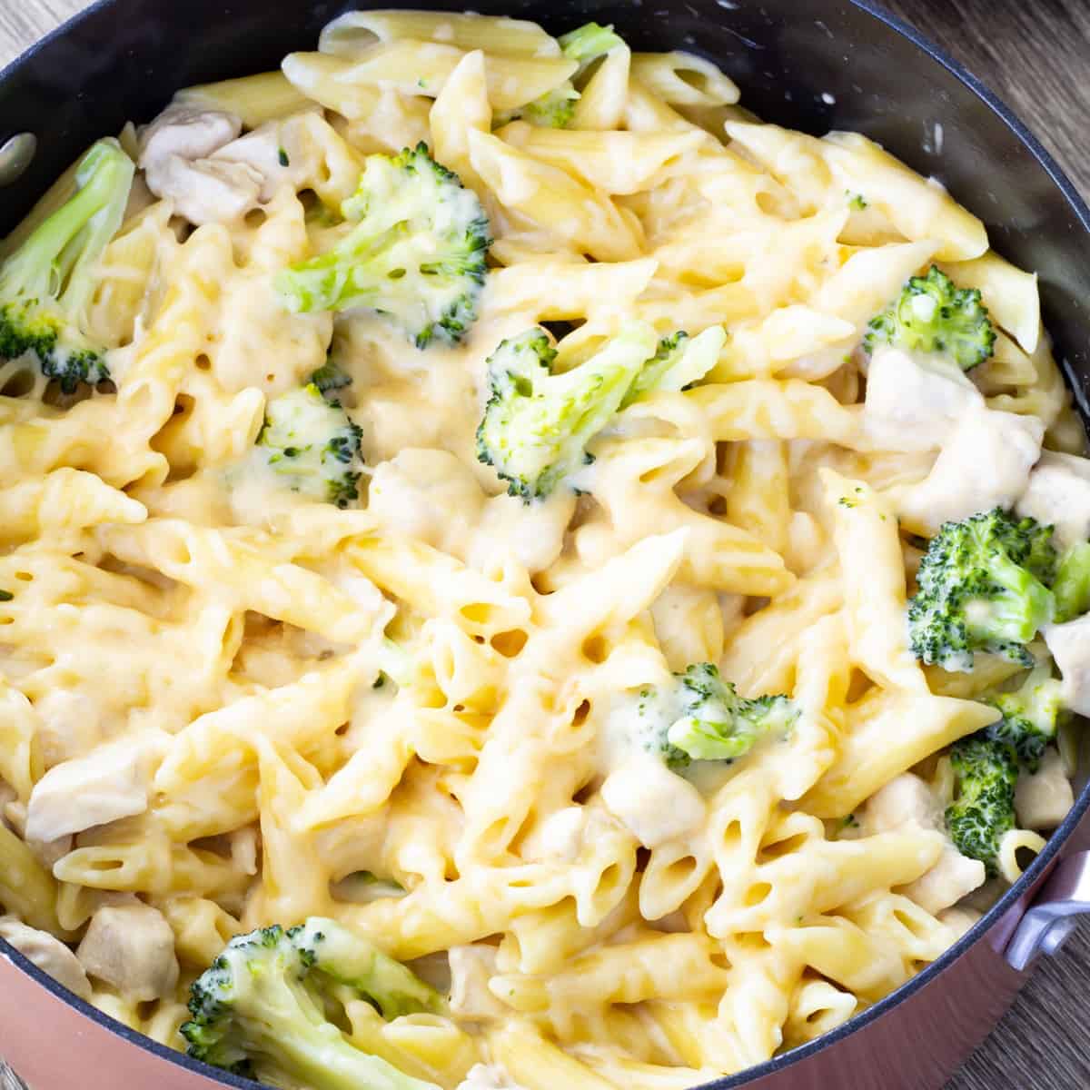 Overhead close up shot of a bronze colored pot full of alfredo chicken broccoli pasta.