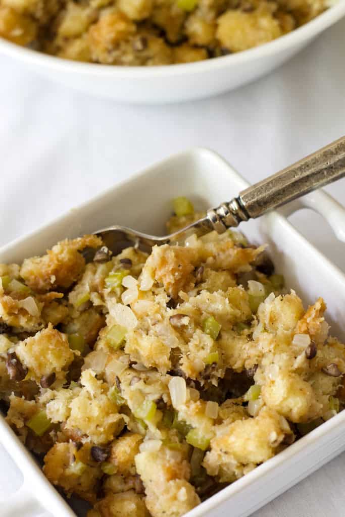 A small square white bowl with stuffing in it and a silver fork. 