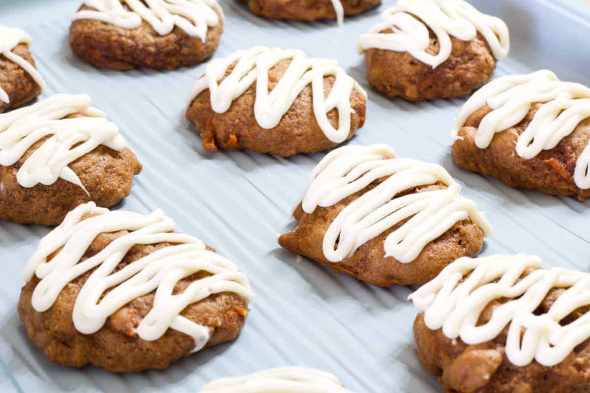 Close up view of frosted Carrot Cake Cookies on a light blue cookie sheet.