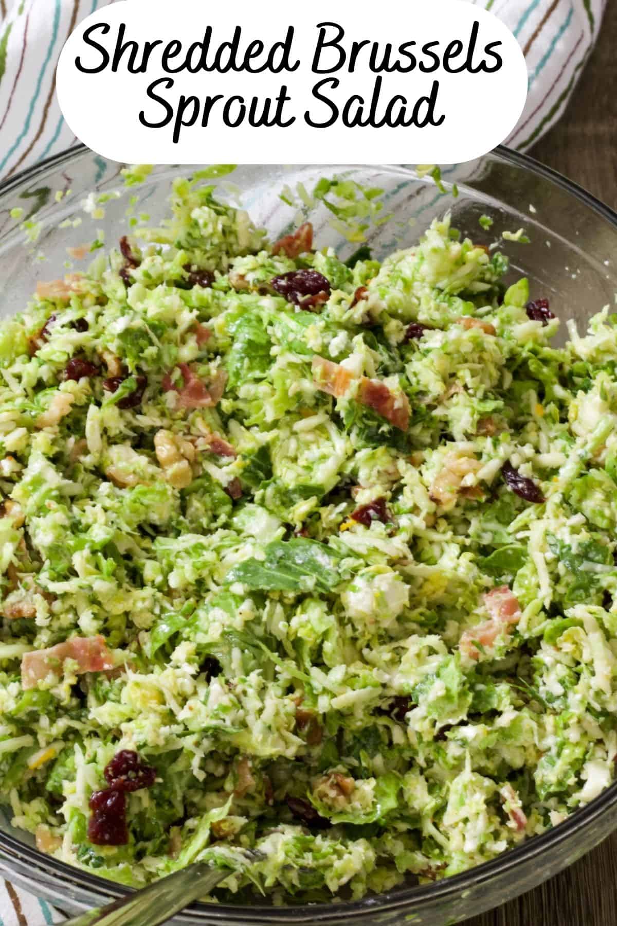 Close up view of a clear glass bowl of brussels sprout salad.