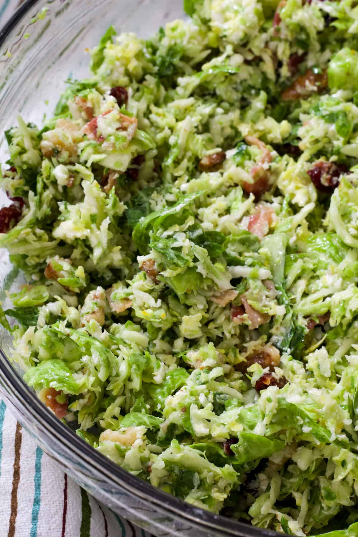 Overheadshot of half a large glass serving bowl with brussels sprout salad.