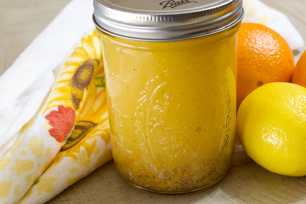 Side view of a jar of salad dressing next to a decorative towel.