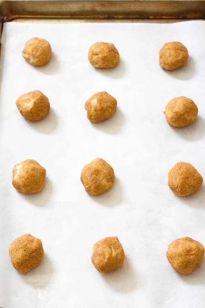 Overhead shot of 1 dozen cookie balls on a sheet pan covered with parchment paper.