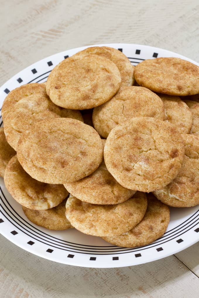 Close up angled view of a plate with many toffee snickerdoodle cookies on it.