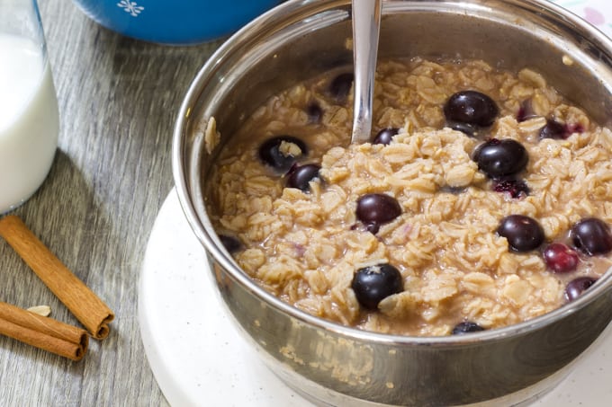 close up shot of a silver saucepan with blueberry oatmeal in it. 