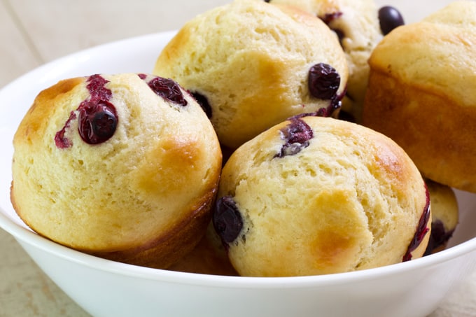 A shallow white bowl filled with blueberry muffins.