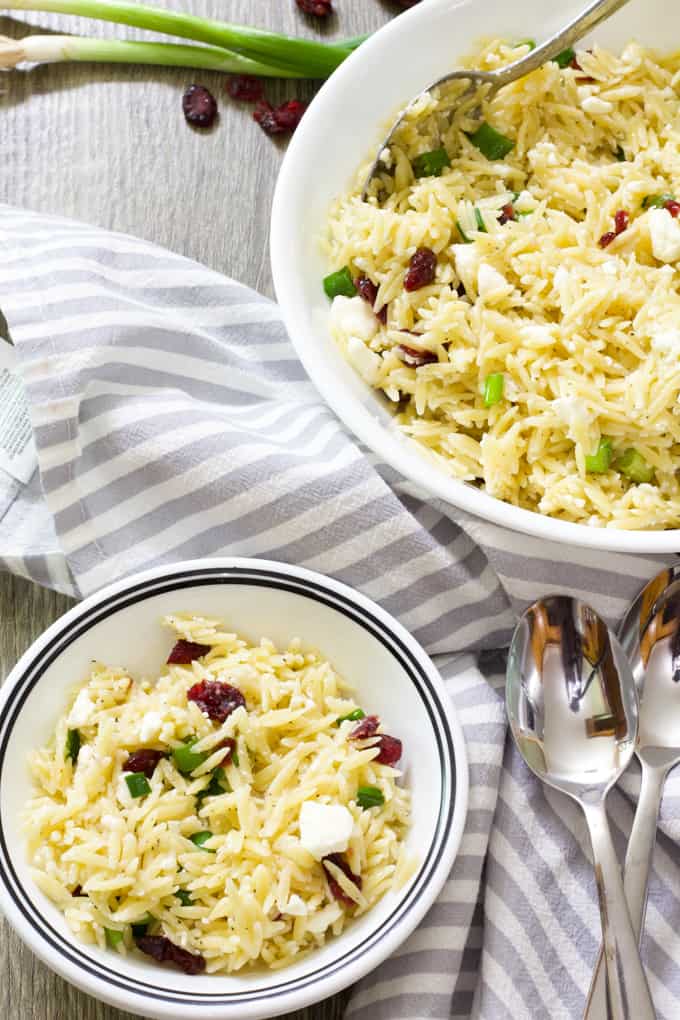 One large and one small bowl qith orzo salad with feta and dried cranberrries.