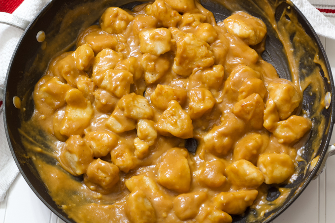 A nonstick skillet filled with peanut butter chicken.