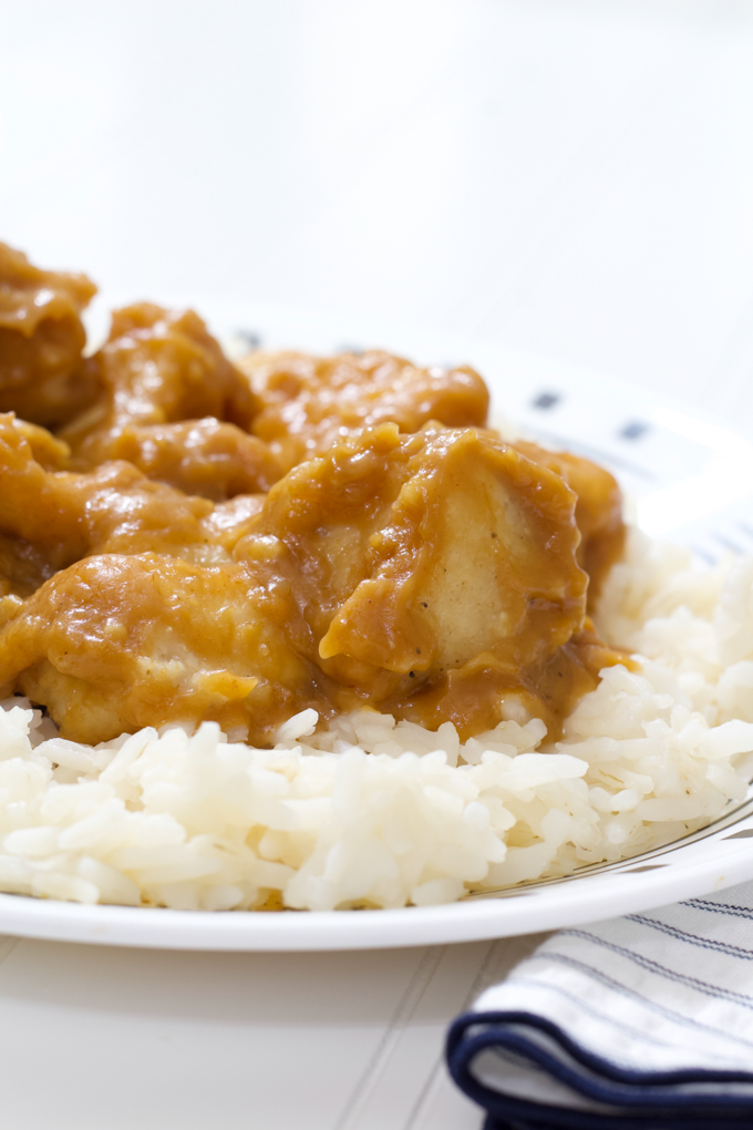 A very close up side view of the peanut butter chicken on a bed of white rice.