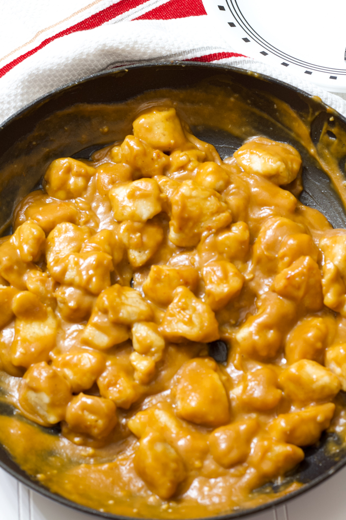 A vertical shot of a skillet with peanut butter chicken in it.