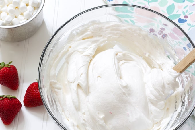 Cool Whip folded into the cream cheese mixture in a bowl.