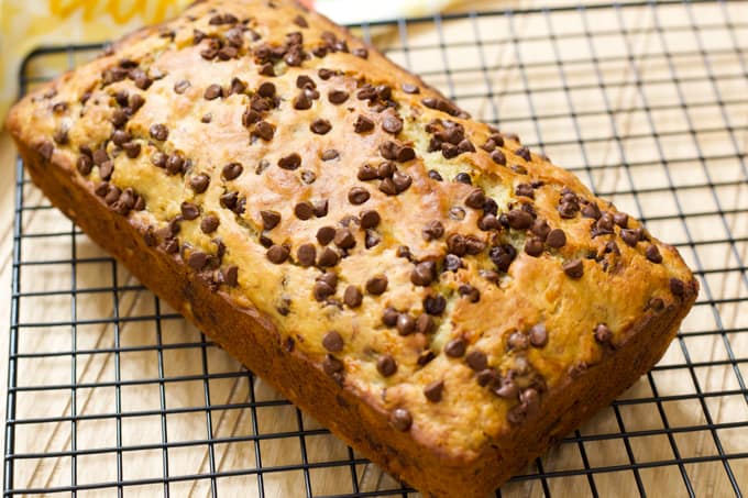 A whole uncut loaf of chocolate chip banana bread on a cooling rack.
