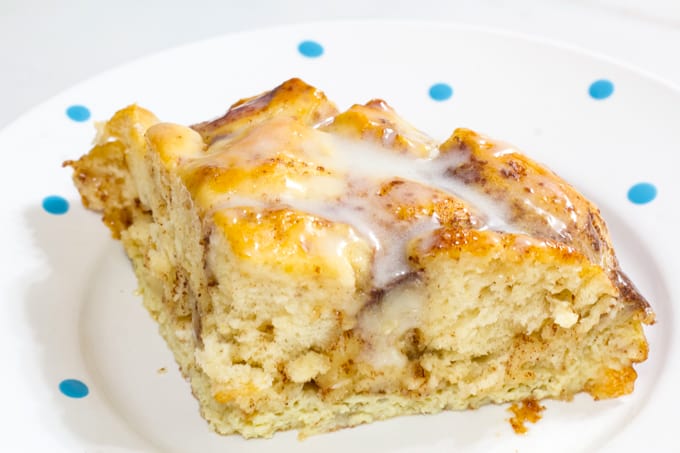 One serving of cinnamon roll breakfast casserole on a white plate with blue dots.