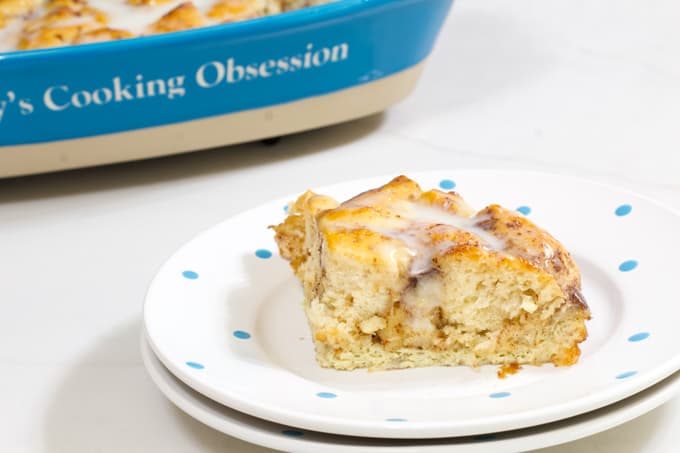 Side view of one serving of casserole in a white plate and the dish with the rest of the casserole in the background.