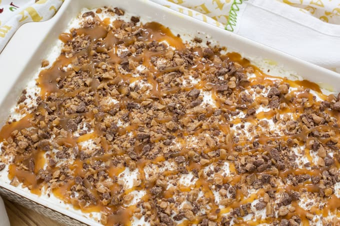 The entire uncut butter brickle poke cake in a stoneware casserole dish.