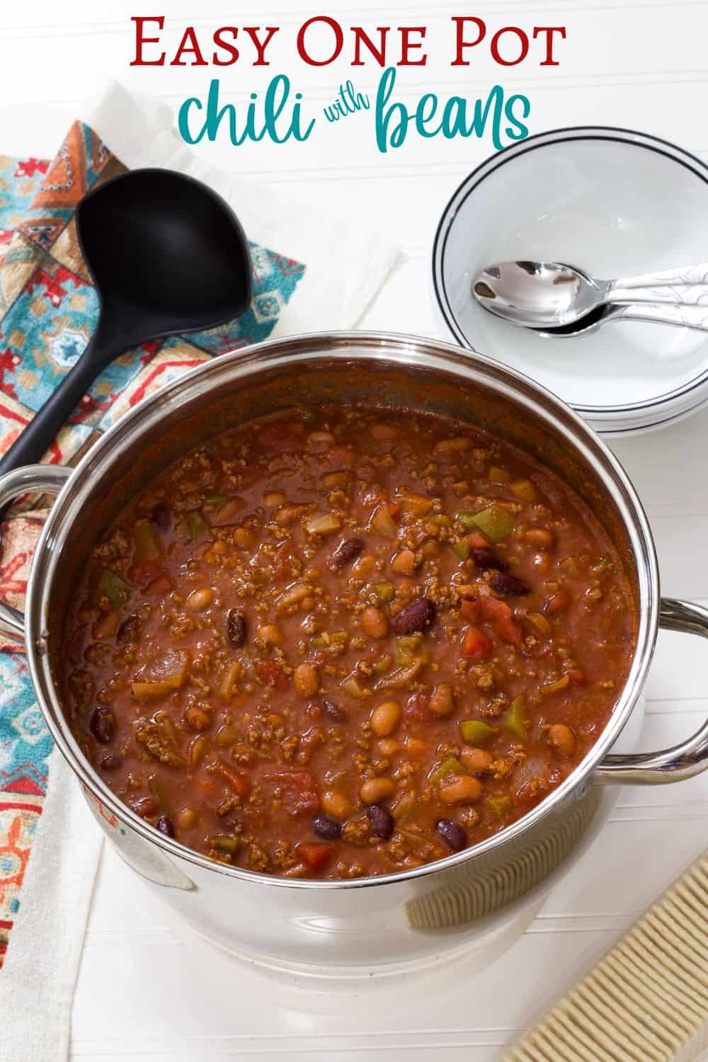 A large pot of chili, bowls to serve it in and crackers on the side.