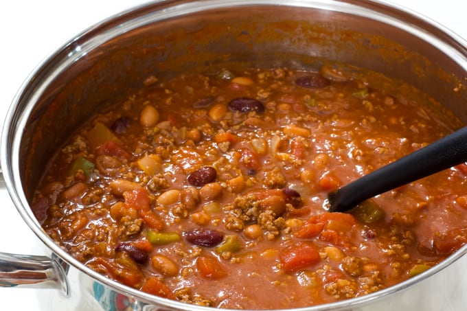 Close up of a silver dutch oven filled with chili with beans