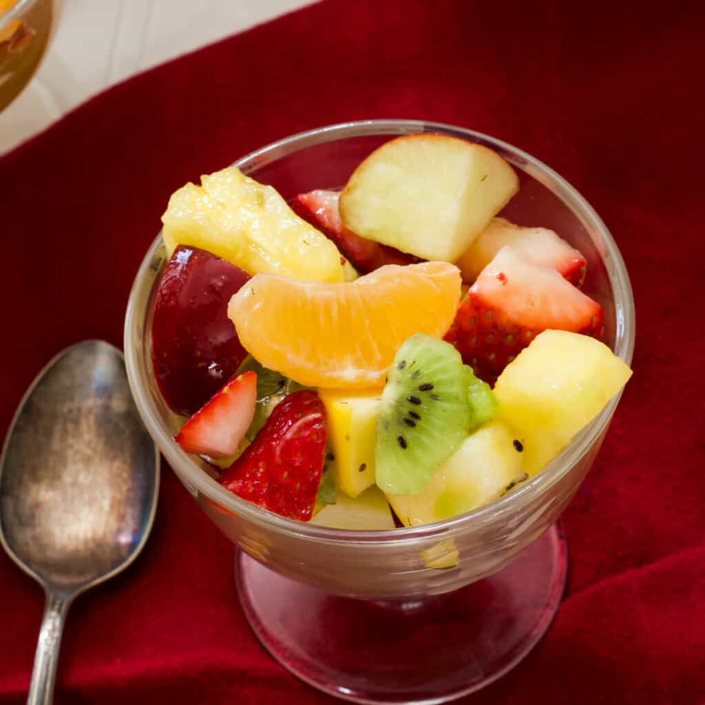 Close up overhead view on a small glass dessert bowl filled with fruit salad.