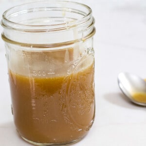 Close up view of the side of a mason jar filled with caramel sauce.