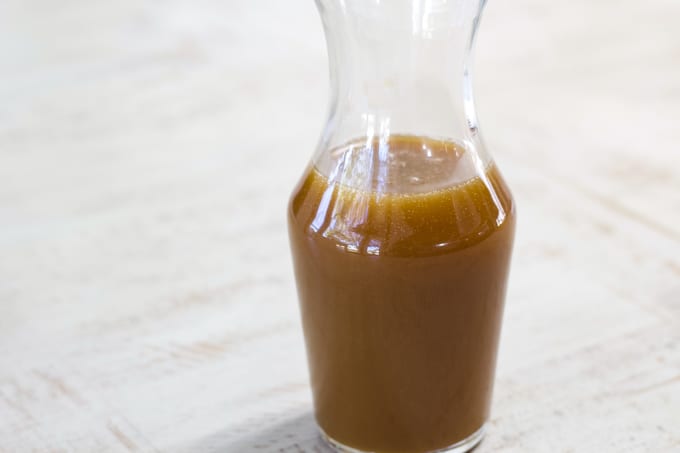 Close up of a small glass clear bottle filled with starbucks caramel sauce.